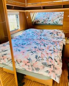 - un lit avec une couette à fleurs sur un bateau dans l'établissement Żuczkowa Przyczepa - maszoperia, à Hel