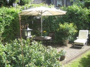 une terrasse avec une table, un parasol et une chaise dans l'établissement 4-Jahreszeiten-Idylle Ollsen, à Hanstedt