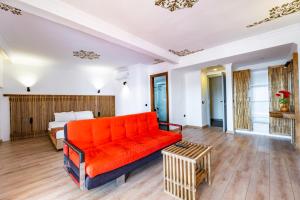 an orange couch in a living room with a bed at Costa Bitezhan Hotel - All Inclusive in Bitez