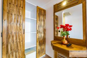 a bathroom with a mirror and a vase with red flowers on a wooden counter at Costa Bitezhan Hotel - All Inclusive in Bitez