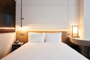 a bedroom with a large white bed and a desk at Nine Tree Premier ROKAUS Hotel Seoul Yongsan in Seoul