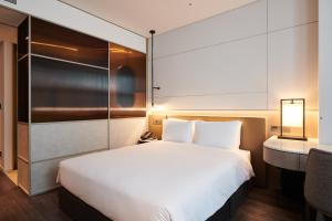 1 dormitorio con 1 cama blanca grande y escritorio en Nine Tree Premier ROKAUS Hotel Seoul Yongsan en Seúl