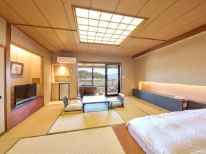 a bedroom with a bed and a television in a room at Fugaku Hanabusa in Izunokuni