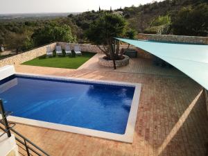uma piscina com cadeiras e um guarda-sol azul em Casa Camé em São Bartolomeu de Messines