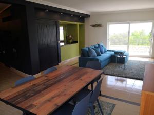 sala de estar con mesa de madera y sofá azul en Casa Camé, en São Bartolomeu de Messines