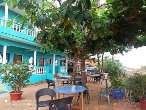 een blauw gebouw met tafels en stoelen onder een boom bij Dee Joy's Beach Place in Calangute