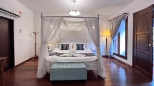 a bedroom with a white canopy bed with a blue stool at 19th Century Boutique Hotel in Melaka