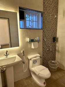 a bathroom with a toilet and a sink and a mirror at Ponmari Villa in Ooty +9 photos