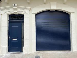 Deux portes bleues de garage sur le côté d'un bâtiment dans l'établissement Studio pratique, Garage gratuit, Esprit Auber, à Béziers
