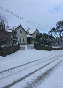 a house with a fence and a yard covered in snow at clover cottage in Kinsale