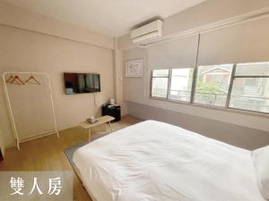 - une chambre avec un lit blanc et une télévision dans l'établissement 度小日, à Tainan