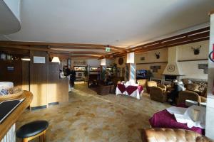 Hotel lo Stambecco في بيريول تشيرفينيا: غرفة معيشة مع كنب وكراسي في غرفة