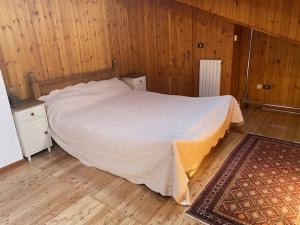 a bedroom with a white bed and wooden walls at Casa OLMA in Aosta