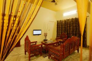 a living room with a table and chairs and a television at Royal Home Stay Gomathipuram in Madurai