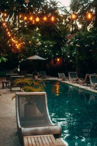 a swimming pool with chairs and lights in a resort at Belukar Villas in Gili Trawangan