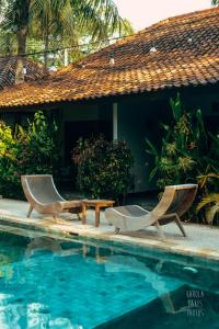 duas cadeiras e uma mesa ao lado de uma piscina em Belukar Villas em Gili Trawangan