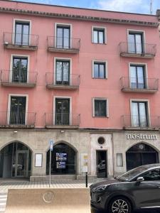 een roze gebouw met een auto ervoor geparkeerd bij Piso céntrico y acogedor in Figueres