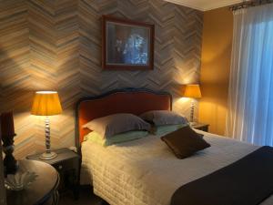 奥雷龙圣乔治L'enclos Des Lys, Villa Raffinée Proche de la Mer, Linge Inclus的一间卧室配有一张带两盏灯和条纹墙的床