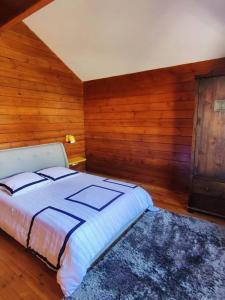 1 dormitorio con 1 cama y pared de madera en Le Chalet des Cévennes, en La Plaine des Cafres