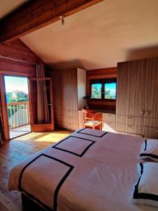 Le Chalet des Cévennes في لا بلين دو كافريه: غرفة نوم بسرير كبير في غرفة بها نوافذ