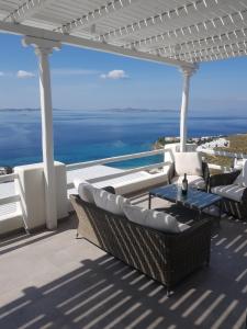 un patio con sedie, tavolo e vista sull'oceano di Panoramic View Mykonos a Mykonos Città