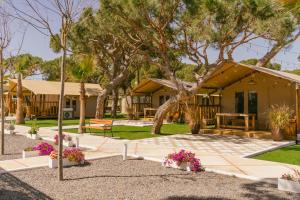 a house with a tree and flowers in front of it at Camping Playa La Bota in Punta Umbría