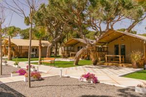 uma casa com uma árvore e flores à frente dela em Camping Playa La Bota em Punta Umbría