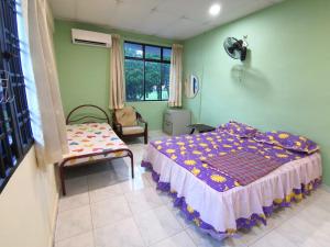 a bedroom with a bed and a chair and a window at Cosy Homestay Ulu Tiram in Ulu Tiram