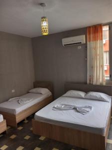 2 Einzelbetten in einem Zimmer mit Fenster in der Unterkunft Apartament in Shëngjin