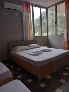 een slaapkamer met een groot bed in een kamer met ramen bij Apartament in Shëngjin