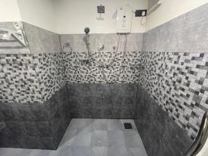 een badkamer met een douche en betegelde muren bij Saga Homestay in Kurundankulama