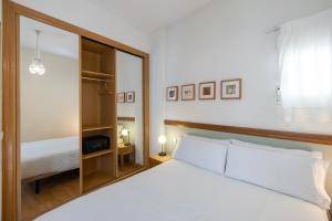 sypialnia z dużym białym łóżkiem i lustrem w obiekcie Oriente Suites w Madrycie
