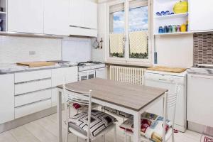 a white kitchen with a wooden table and chairs at Villa Gardesana Torri del Benaco in Torri del Benaco