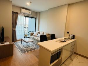 een keuken en een woonkamer met een bank en een tafel bij new sky pool gym sauna condo with 1 bedroom in city in Chiang Mai