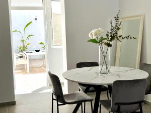 una mesa de comedor blanca con un jarrón de flores. en Stasinou 52, en Limassol