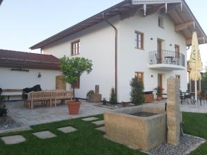 a large white house with a courtyard with a bench at Ferienwohnungen Schneckenhausen in Pittenhart