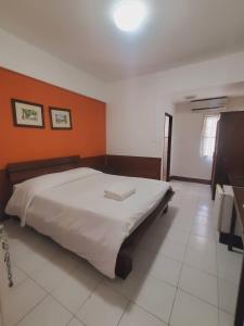 a bedroom with a large bed with an orange wall at Mali's Room in Chiang Mai