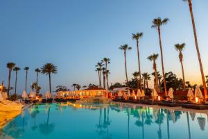a pool with umbrellas and palm trees at a resort at Pavlo Napa Beach Hotel in Ayia Napa