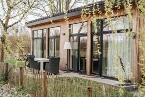 una casa de cristal con mesa y sillas en un jardín en Trendy chalet aan visvijver, en Hamme