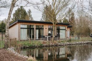 a tiny house next to a body of water at Trendy chalet aan visvijver in Hamme