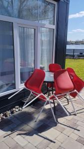 two red chairs and a table on a patio at Add Story Guest House in Rēzekne