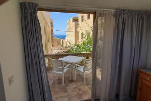 een tafel en stoelen op een balkon met een raam bij Villa Bronja Superior Airconditioned Studio apartment in Xlendi in Xlendi
