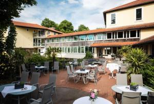 eine Terrasse mit Tischen und Stühlen und ein Gebäude in der Unterkunft Hotel Weserschlösschen in Nienburg