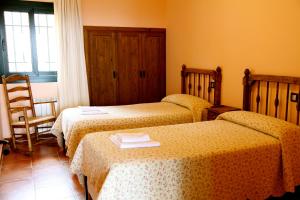 een hotelkamer met 2 bedden en een stoel bij Las Casas de Agapito in Poyales del Hoyo