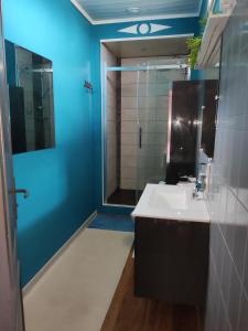 La salle de bains est pourvue d'un lavabo blanc et d'un mur bleu. dans l'établissement Les Bibasses, à Aillas