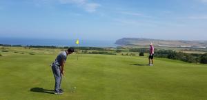 dos personas jugando golf en un campo de golf en Hunley Golf Club, en Saltburn-by-the-Sea