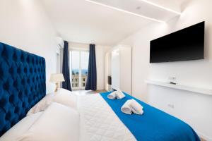 - une chambre avec un lit bleu et blanc et une télévision à écran plat dans l'établissement The Attico, à Sorrente