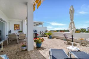 un patio de apartamentos con sillas y sombrilla en Lujoso apartamento con alucinantes vistas al golf - Iwii A 38 en Marbella