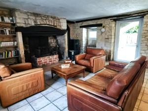 sala de estar con muebles de cuero y chimenea en Les chambres du Roc, en Le Roc