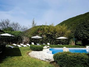 una piscina con sillas y sombrillas blancas en Les chambres du Roc, en Le Roc